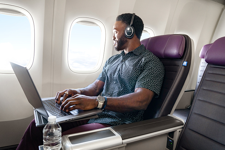 Man in window seat with laptop and headphones